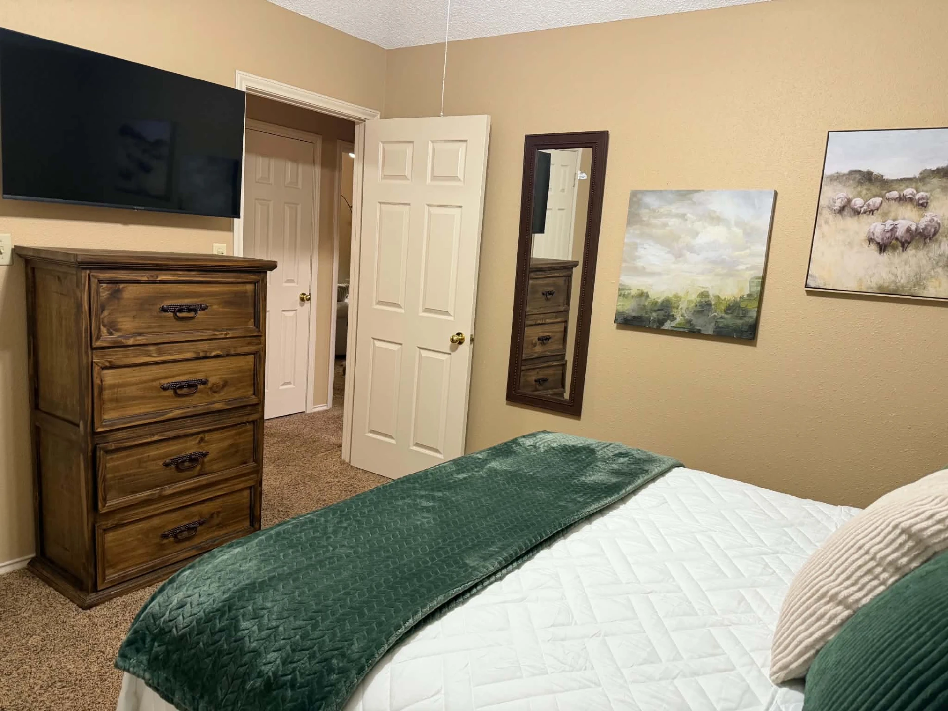 Bedroom 2 — 42" wall-mounted smart TV above a rustic wood dresser