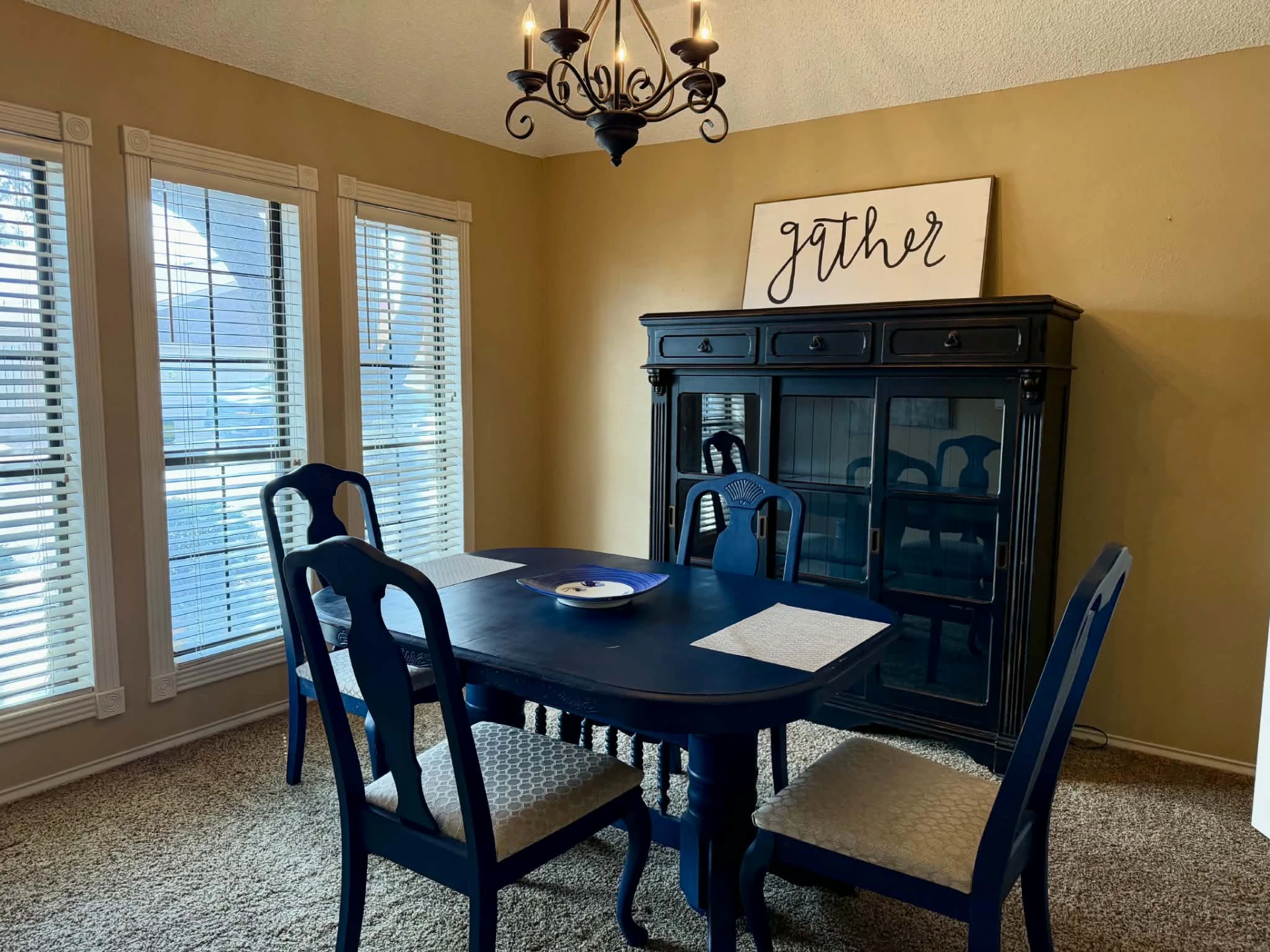 Formal dining room with a dark wood table, upholstered chairs and a wrought-iron chandelier